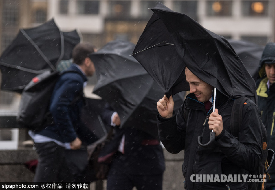 英國(guó)倫敦雨天狂風(fēng)大作 民眾出行雨傘被吹翻